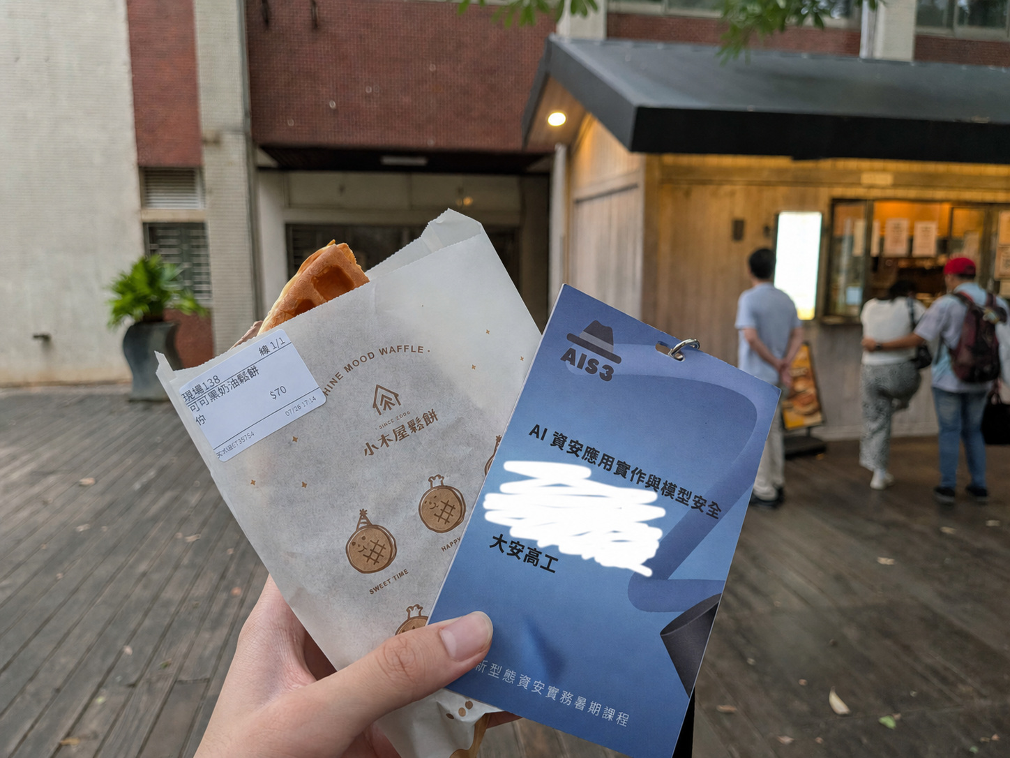 AIS3 下課後,手上拿著鬆餅和活動名牌